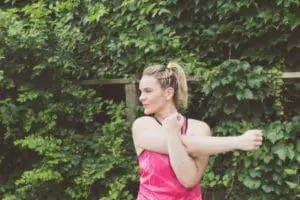 Woman stretching outside in workout gear.