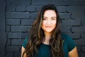 Close-up portrait of a women against dark brick backdrop.