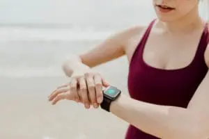 Woman in a sports tank top looking at her smart watch.