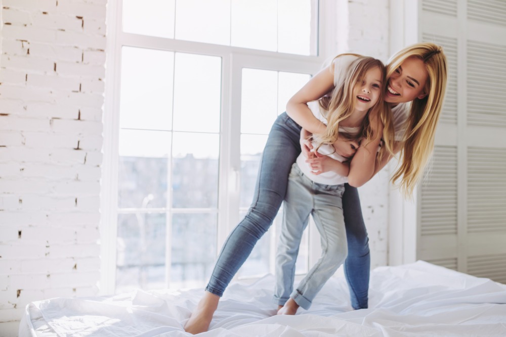 Attractive young woman and her little cute daughter are having fun while being at home together.