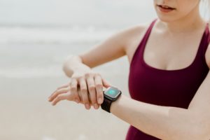 Woman in a sports tank top looking at her smart watch.